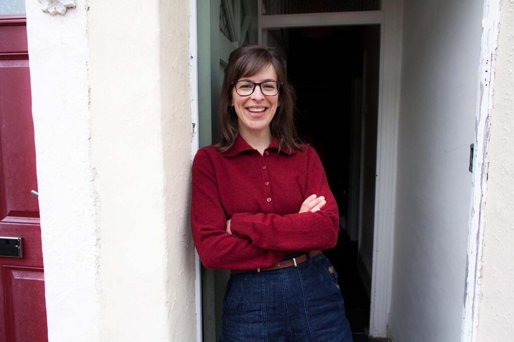 Photo of me standing with crossed arms smiling, at the front door of a house.