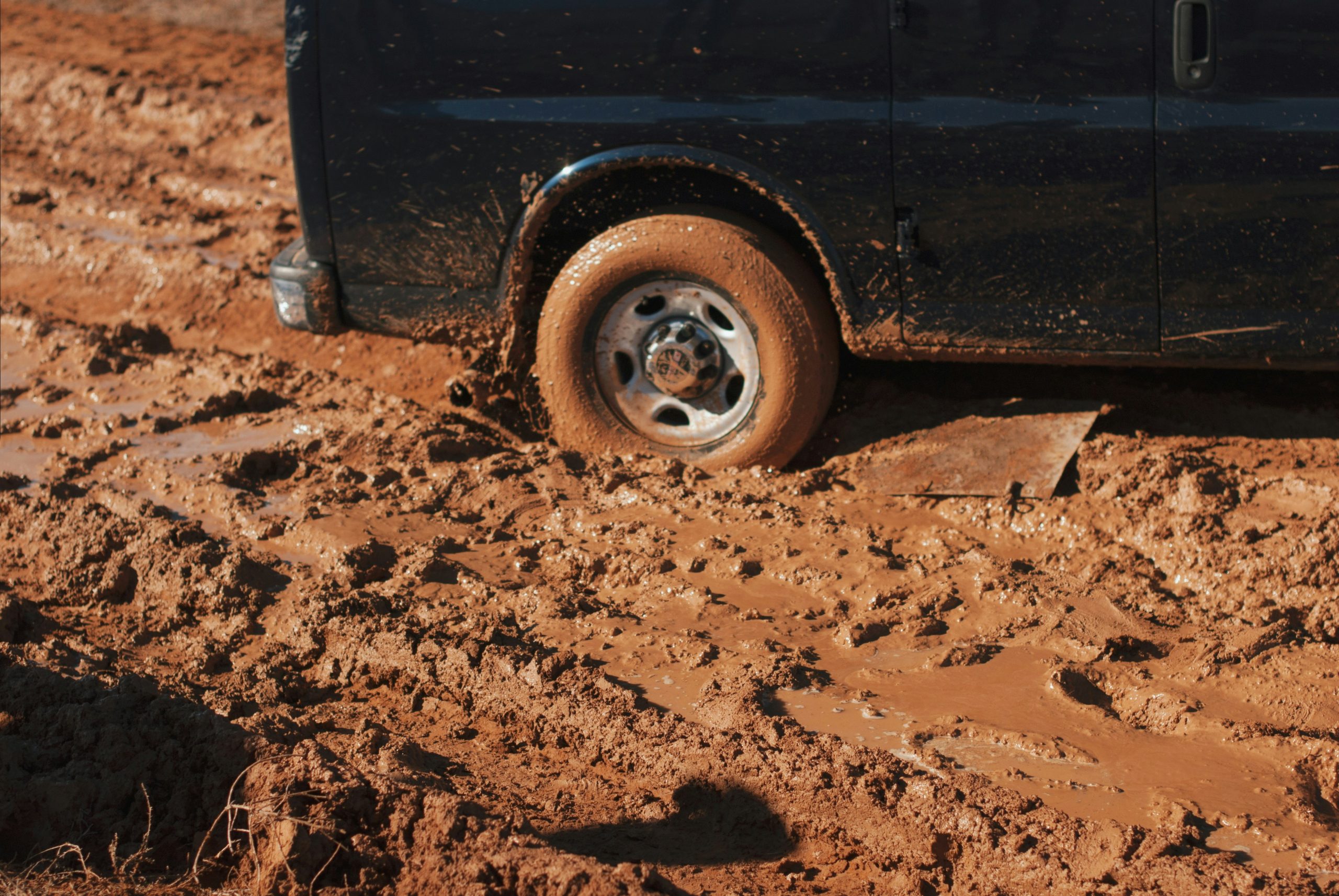 Close up of the wheel of a van stuck in mud