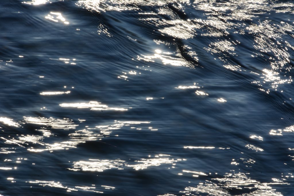 Close up photo of a river running fast - sparkling in the sunshine